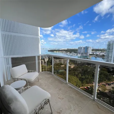 a living room with stainless steel appliances furniture a rug and a kitchen view