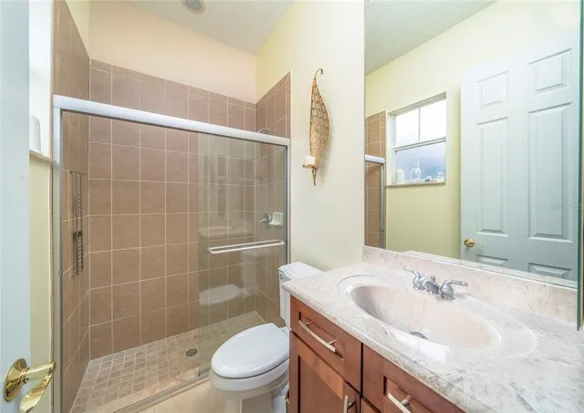 a bathroom with a granite countertop sink a toilet and shower