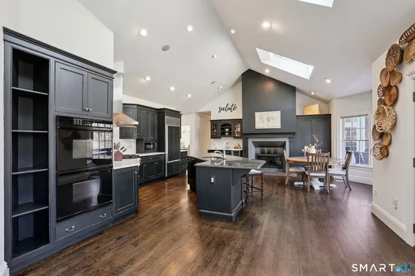 a living room with stainless steel appliances furniture a fireplace a flat screen tv and a kitchen view