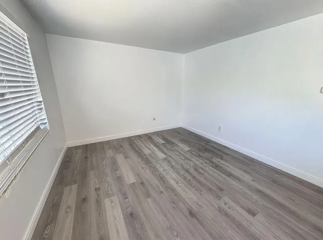 a view of a room that has wooden floor and a window