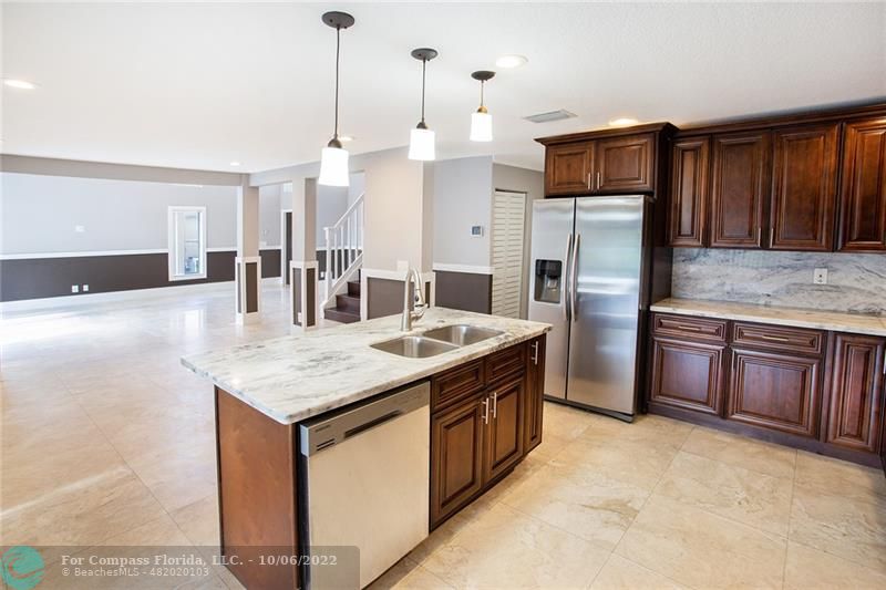 Winston Park Coconut Creek, FL 33073 - Photo 7 of 35 a kitchen with stainless steel appliances kitchen island granite countertop a kitchen island a refrigerator a stove and a sink with wooden cabinets