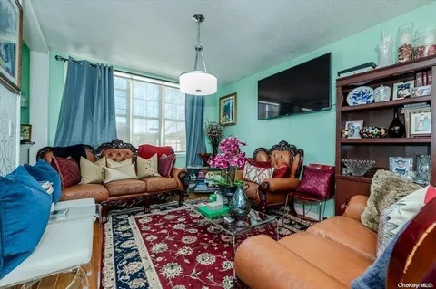 a living room with furniture a flat screen tv and a floor to ceiling window