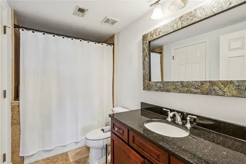 a bathroom with a granite countertop sink toilet and a mirror