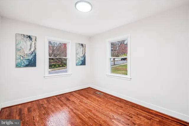 a view of an empty room with window and wooden floor