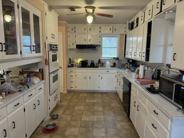 a large kitchen with stainless steel appliances a stove sink and cabinets