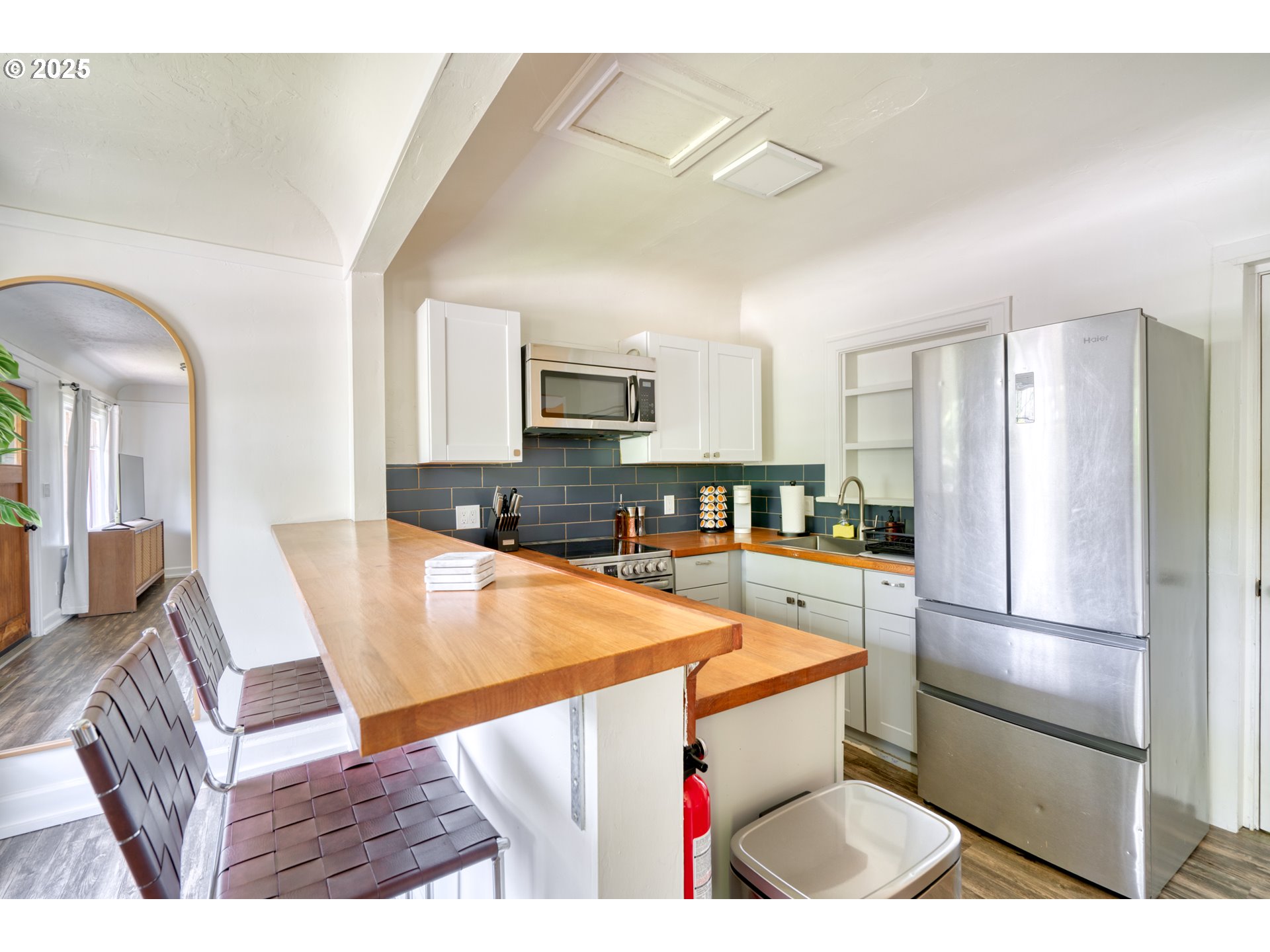 9647 Southwest Capitol Highway Portland, OR 97219 - Photo 31 of 33 a kitchen with a refrigerator a stove top oven a sink dishwasher and white cabinets with wooden floor