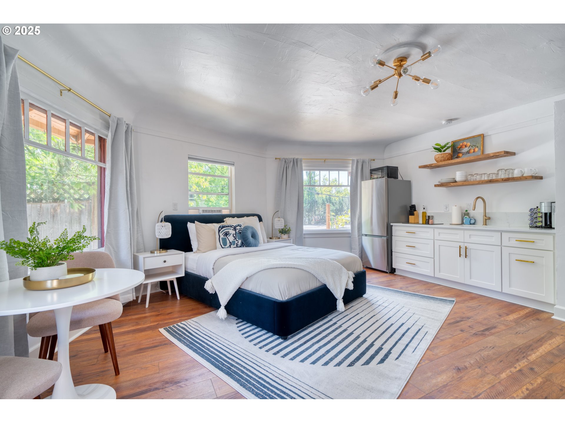 9647 Southwest Capitol Highway Portland, OR 97219 - Photo 6 of 33 a spacious bedroom with a bed a dresser and potted plant with the wooden floor