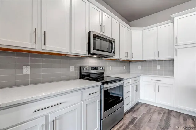 a kitchen with stainless steel appliances granite countertop grey cabinets a stove a sink and dishwasher
