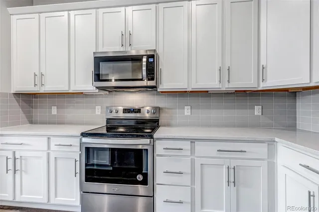 a kitchen with white cabinets and stainless steel appliances
