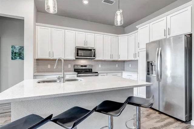 a kitchen with stainless steel appliances a refrigerator a sink a stove a microwave a dining table and chairs