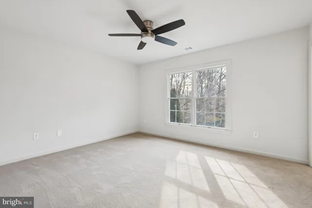 an empty room with a ceiling fan and window