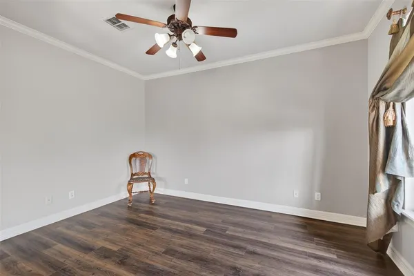an empty room with wooden floor and ceiling fan