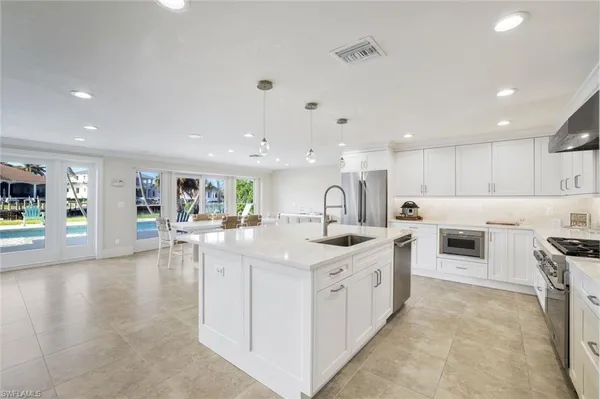 a large white kitchen with a stove top oven a sink a dining table and chairs