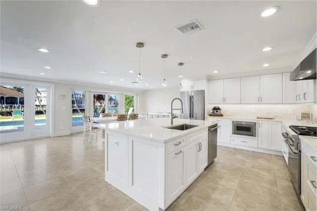 a large white kitchen with a stove top oven a sink a dining table and chairs