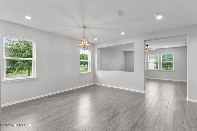 an empty room with wooden floor ceiling fan and windows