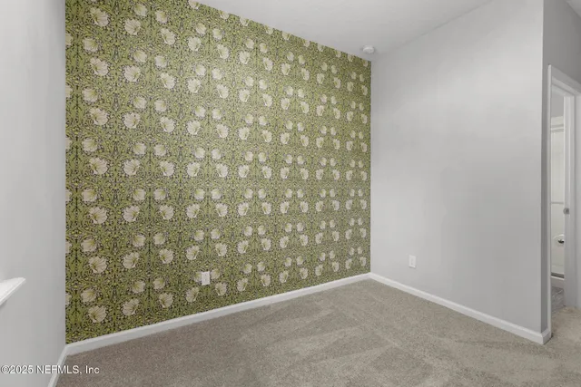 a view of an empty room with wooden floor and a ceiling fan
