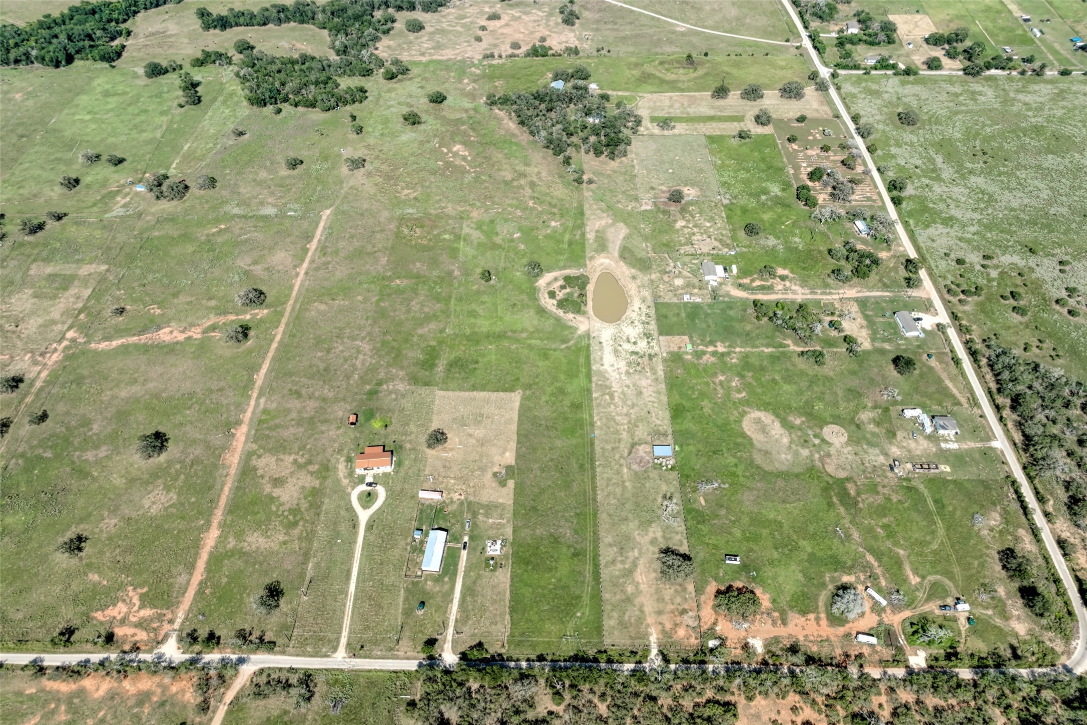 5309 Tenney Creek Road Luling, TX 78648 - Photo 14 of 23 Vast green fields stretch out under the sun, featuring a tranquil pond.