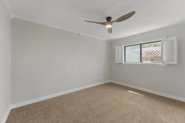 an empty room with a window and a ceiling fan