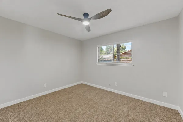 an empty room with a window and a ceiling fan