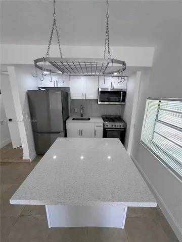a large kitchen with a stove a refrigerator and a chandelier
