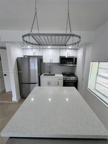 a kitchen with stainless steel appliances a kitchen island a stove a microwave and a refrigerator