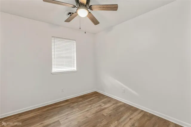 an empty room with a window and a fan