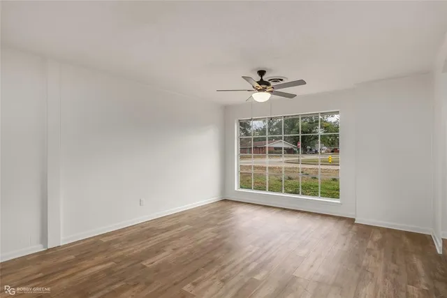 an empty room with wooden floor and ceiling fan