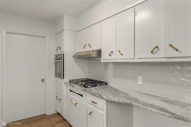 a kitchen with granite countertop white cabinets and a stove