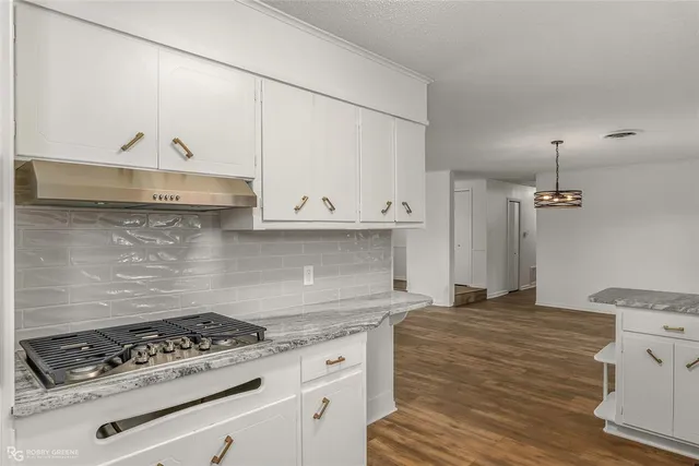 a kitchen with granite countertop a stove and a white cabinets