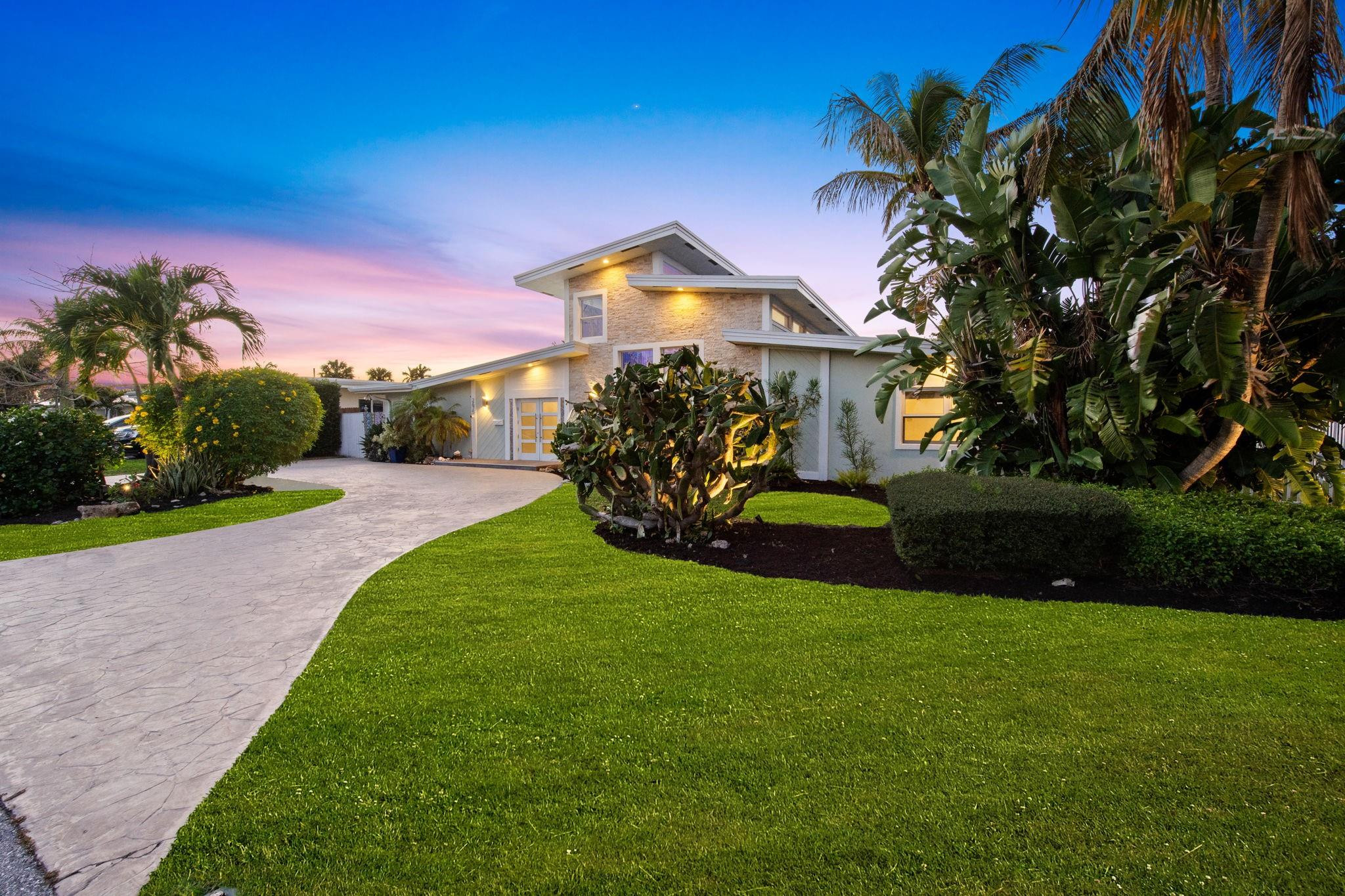 2675 Northeast 24th Street Lighthouse Point, FL 33064 - Photo 19 of 48 a front view of a house with a garden and yard
