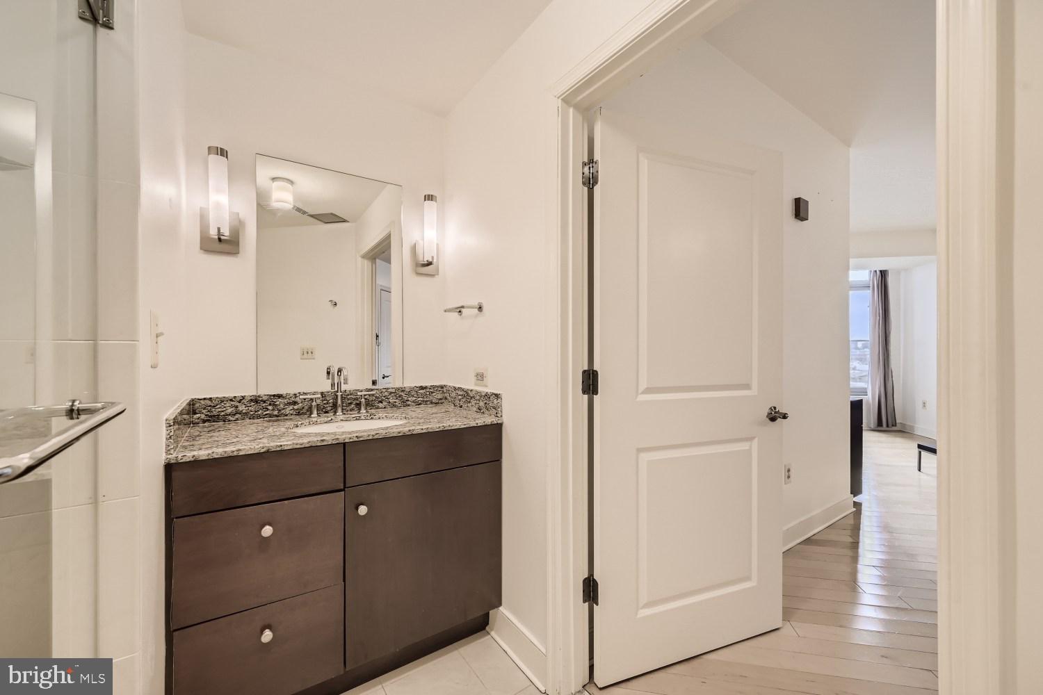 675 President Street, Unit 2107 Baltimore, MD 21202 - Photo 21 of 39 a bathroom with a granite countertop sink a mirror and a shower