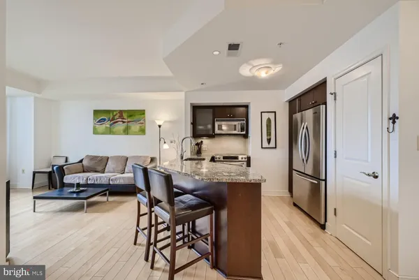 a living room with furniture a refrigerator and a wooden floor