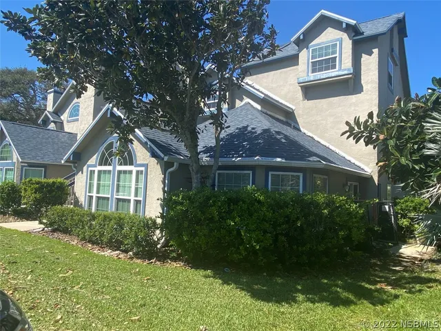 a front view of a house with a yard and trees