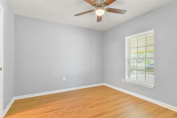 an empty room with a window and a fan