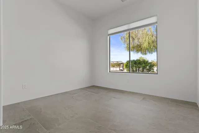 an empty room with chandelier fan and windows
