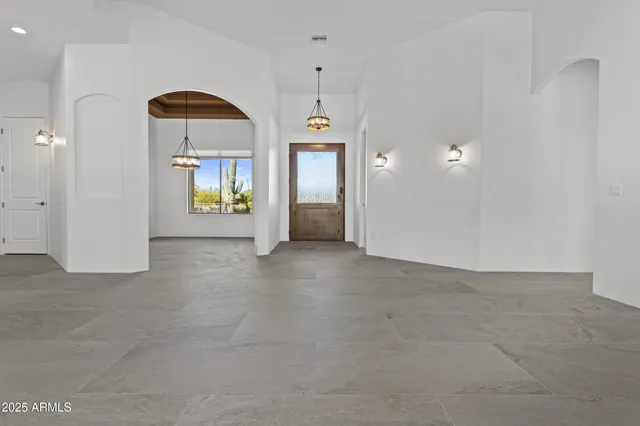 an empty room with windows and chandelier fan