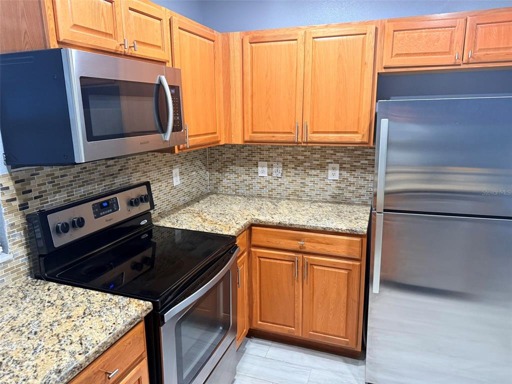 1325 Lyonshire Drive Wesley Chapel, FL 33543 - Photo 4 of 20 a kitchen with granite countertop a stove top oven microwave and cabinets
