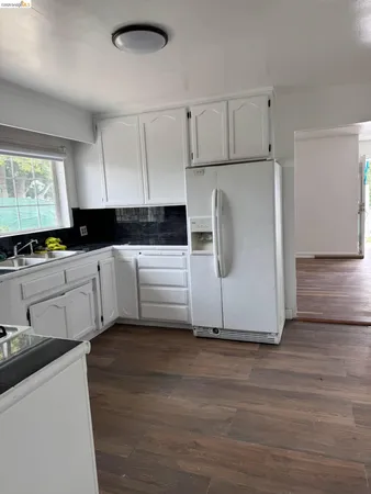 a kitchen with stainless steel appliances white cabinets and wooden floor