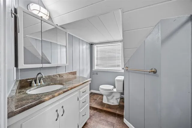 a bathroom with a granite countertop sink mirror vanity and toilet