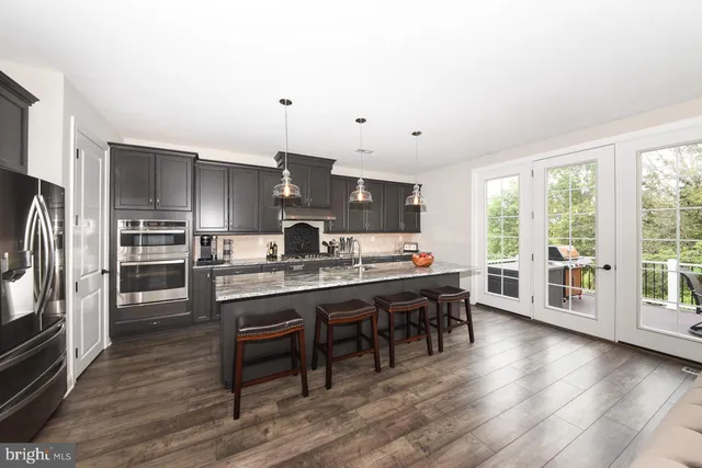 a kitchen with stainless steel appliances a dining table chairs stove refrigerator and cabinets