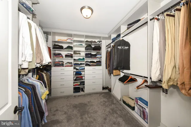 a view of walk in closet with clothes and shoes