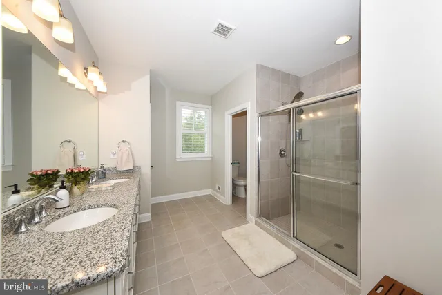a bathroom with a granite countertop sink a mirror and shower