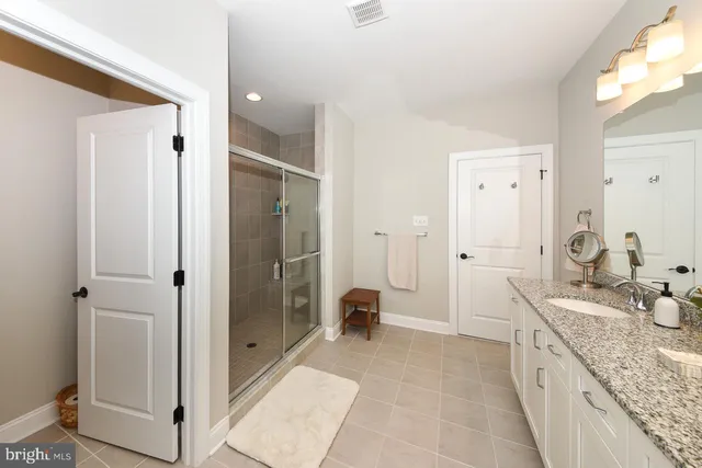 a spacious bathroom with a granite countertop double vanity sink mirror and shower