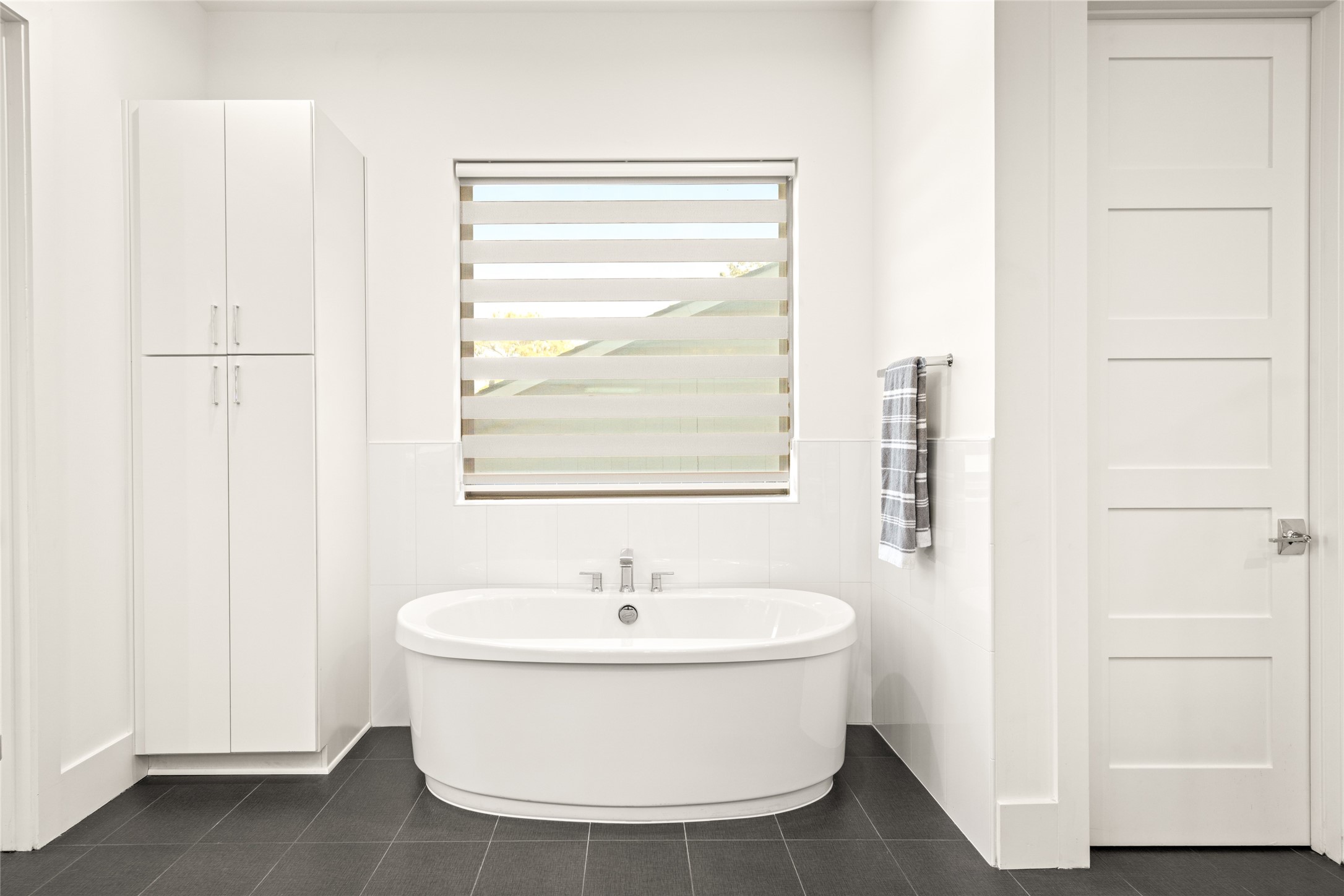 5706 Birdwood Road Houston, TX 77096 - Photo 23 of 50 This bathroom features a clean line design. The dark floor tiles contrast elegantly with the light walls and doors, creating a bright and inviting space.