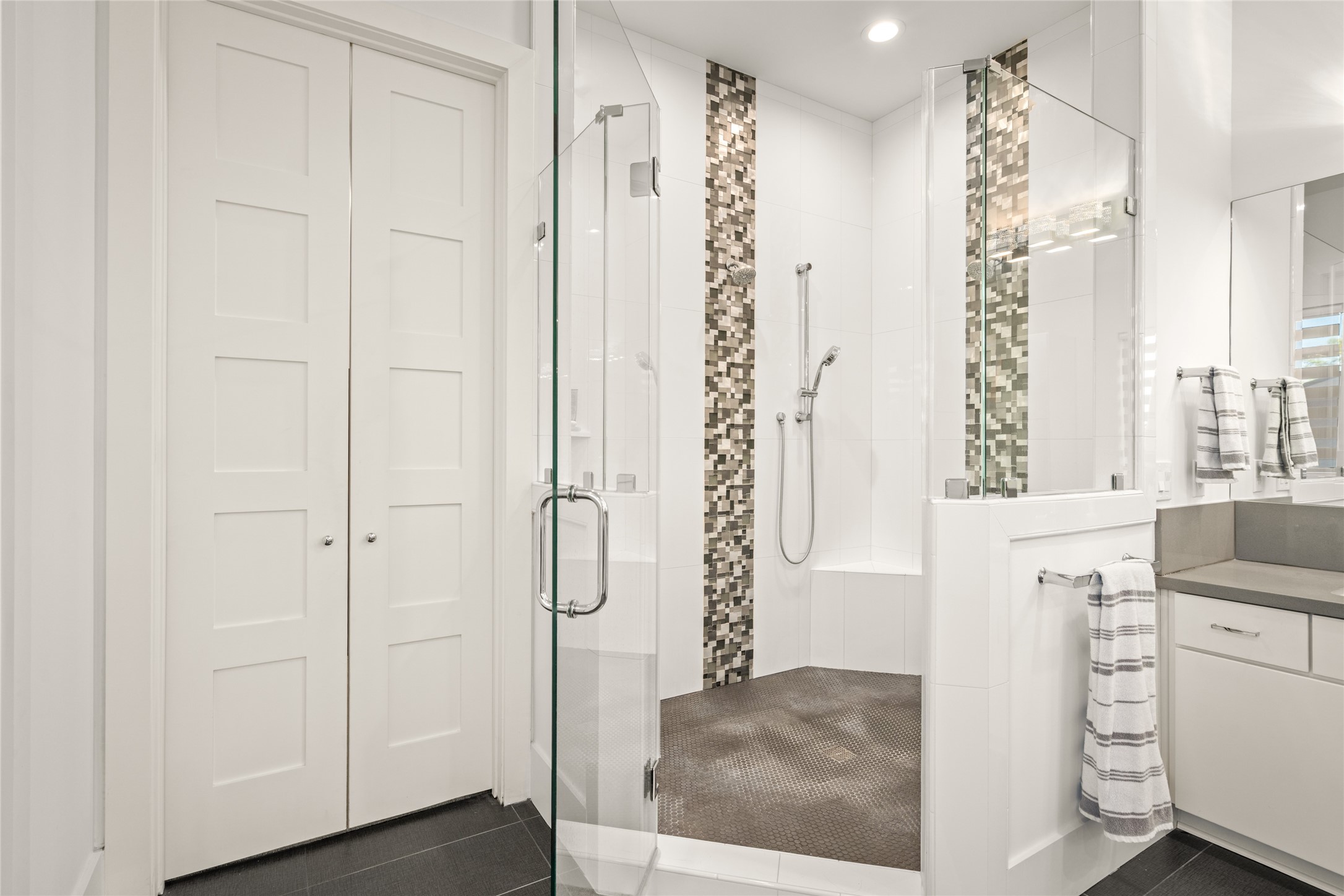 5706 Birdwood Road Houston, TX 77096 - Photo 24 of 50 Amazing frameless glass shower with vertical mosaic tile accents accentuating the ceiling height, shower seat/ledge and body sprayer. Double doors lead to the primary suite closet.