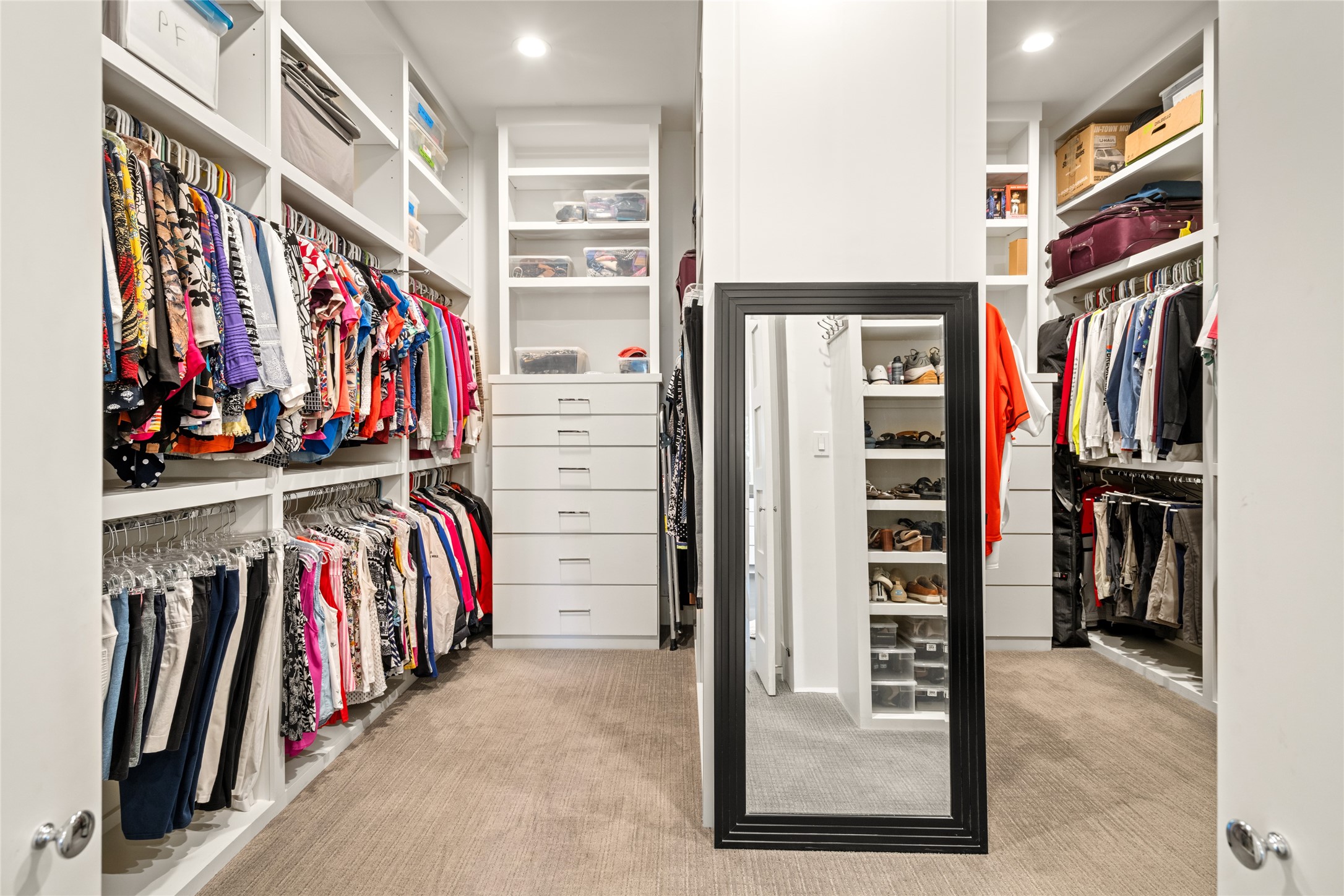 5706 Birdwood Road Houston, TX 77096 - Photo 27 of 50 This spacious walk-in closet features ample shelving, hanging space, and double, floor to ceiling built-ins with drawers and shelves for organized storage. The neutral carpet adds warmth and comfort. Ideal for keeping your wardrobe neatly accessible.