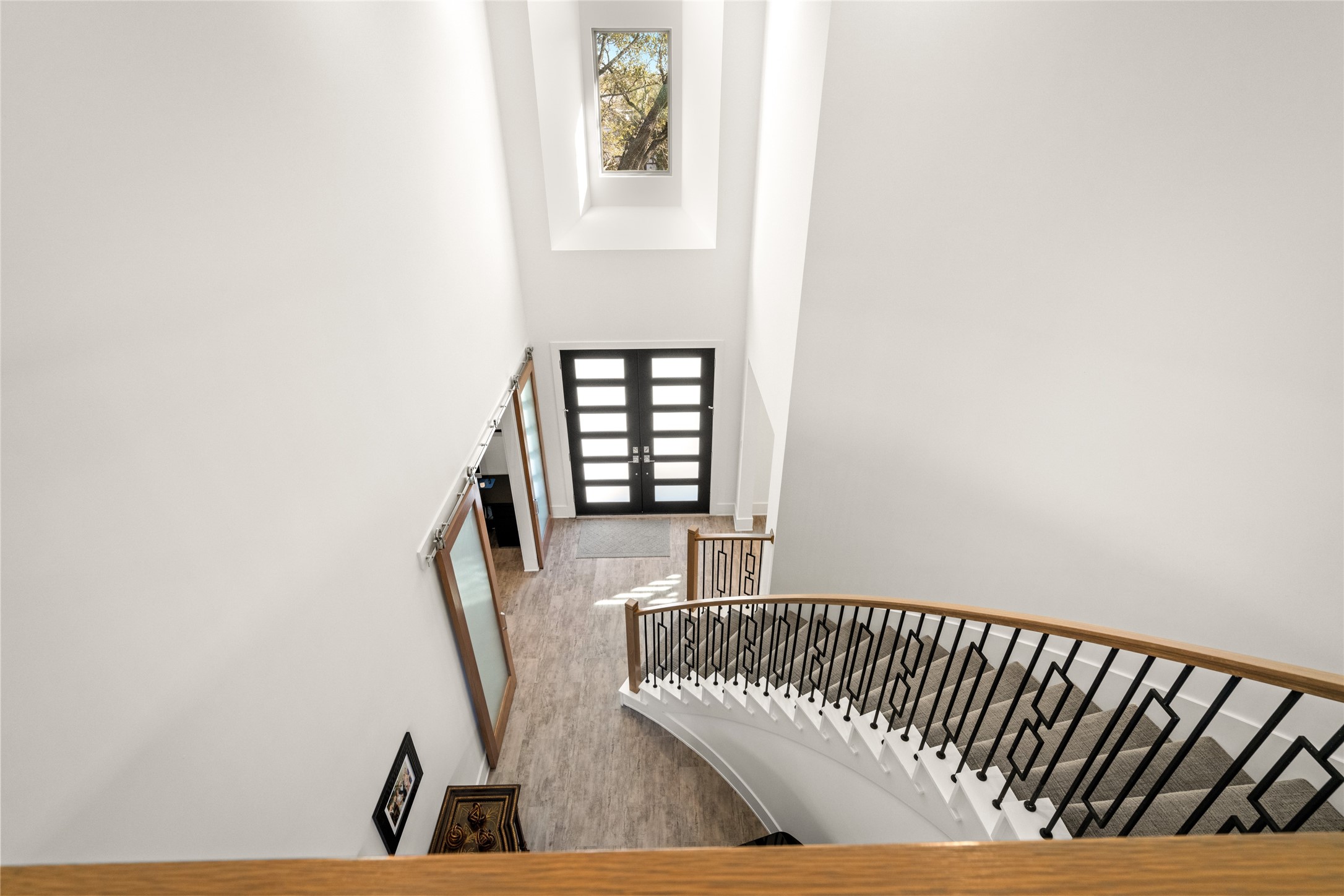 5706 Birdwood Road Houston, TX 77096 - Photo 28 of 50 This photo showcases a bright, spacious foyer with a modern staircase featuring decorative wrought iron railings. Natural light streams through the large window above the front door, creating a very inviting entryway.