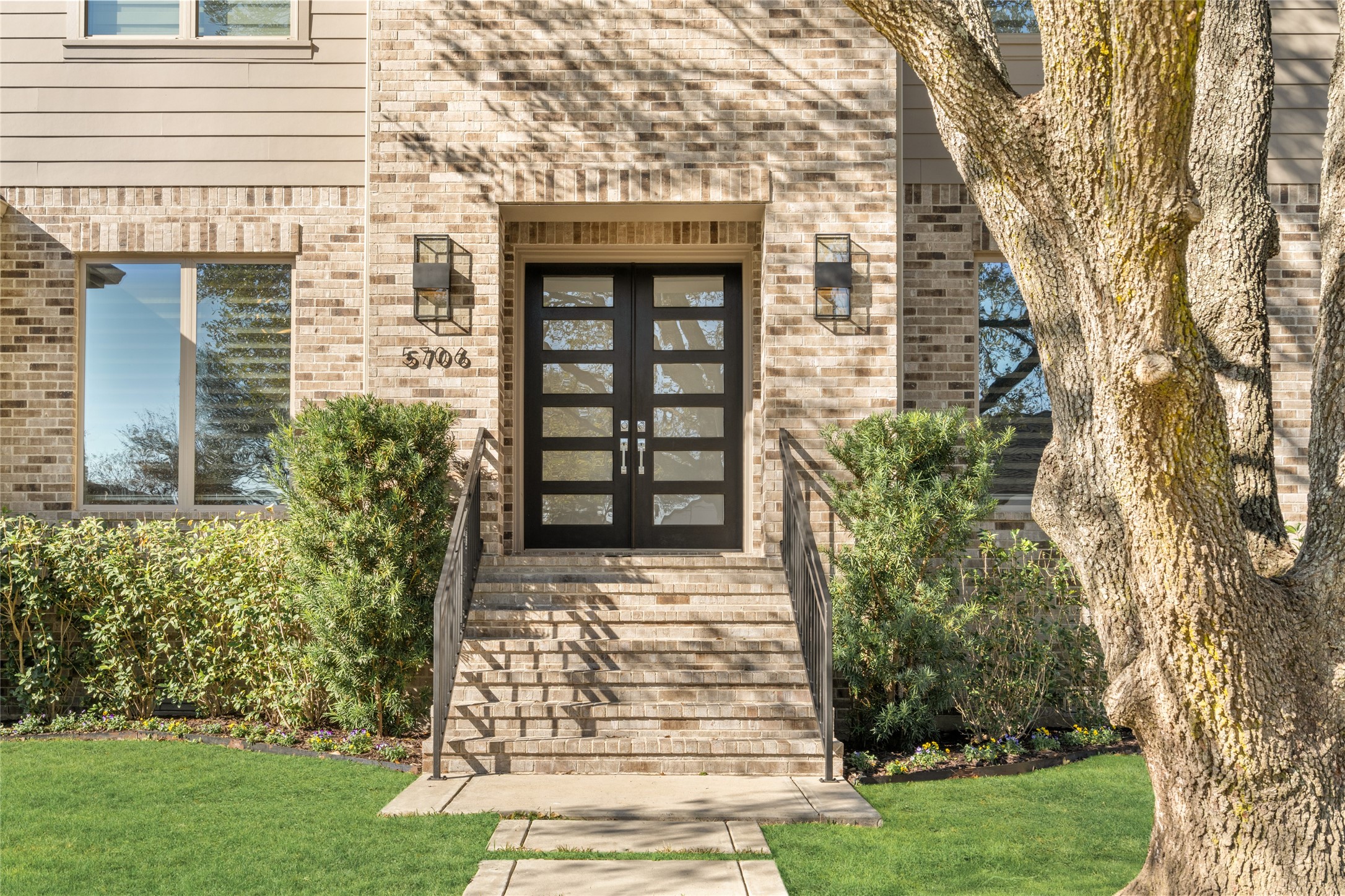5706 Birdwood Road Houston, TX 77096 - Photo 3 of 50 Such a welcoming front entrance. Featuring a set of 6-lite doors with glass panels, flanked by contemporary, designer lighting and lush landscaping. The wrought iron railing on either side compliments the staircase leading up to the entry.