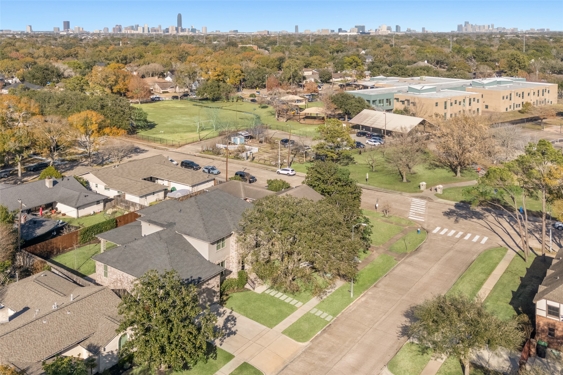 5706 Birdwood Road Houston, TX 77096 - Photo 47 of 50 This aerial photo showcases the neighborhood with tree-lined streets and single-family homes. Herod Elementary School and Gail Reeves Park are visible, and that close! The city skyline in the background suggests proximity to urban conveniences, providing a balance of suburban tranquility and city access. Quick drive to the TX Medical Center and sports venues, shopping, restaurants, are all close by.