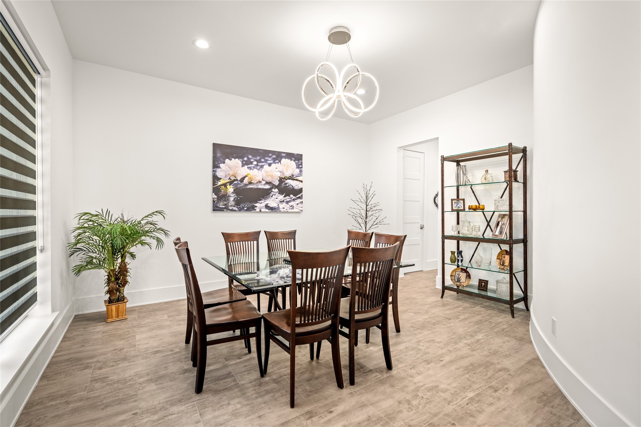 5706 Birdwood Road Houston, TX 77096 - Photo 5 of 50 The open dining room is anchored by the modern designer light fixture and shares the sinuous curved wall of the staircase which lends a softness to the rectilinear lines of the room. Neutral walls, custom shade on the large front window and recessed lighting.